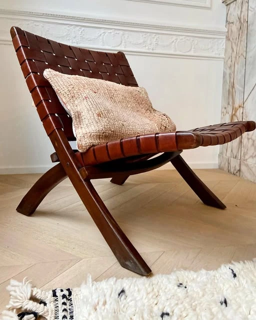 Sculptural wooden lounge chair with a pale cushion