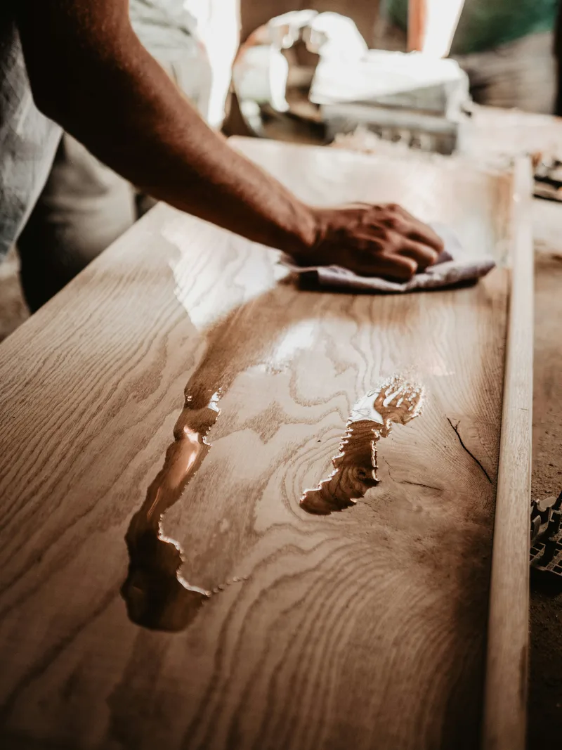Hands carefully sanding a long wooden surface