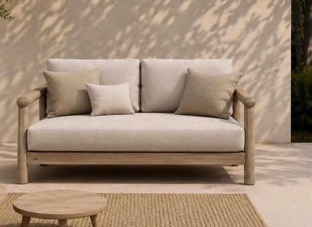 Soft neutral sofa with wooden frame, against a textured wall